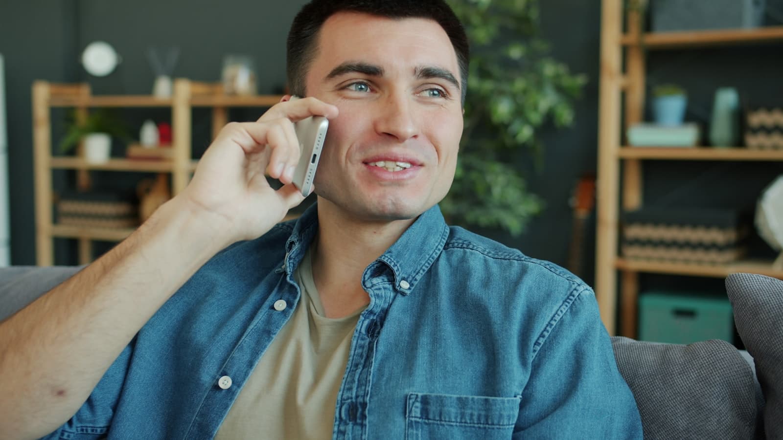 Man sitting on a sofa at home talking on a mobile phone, relaxed and mid-conversation